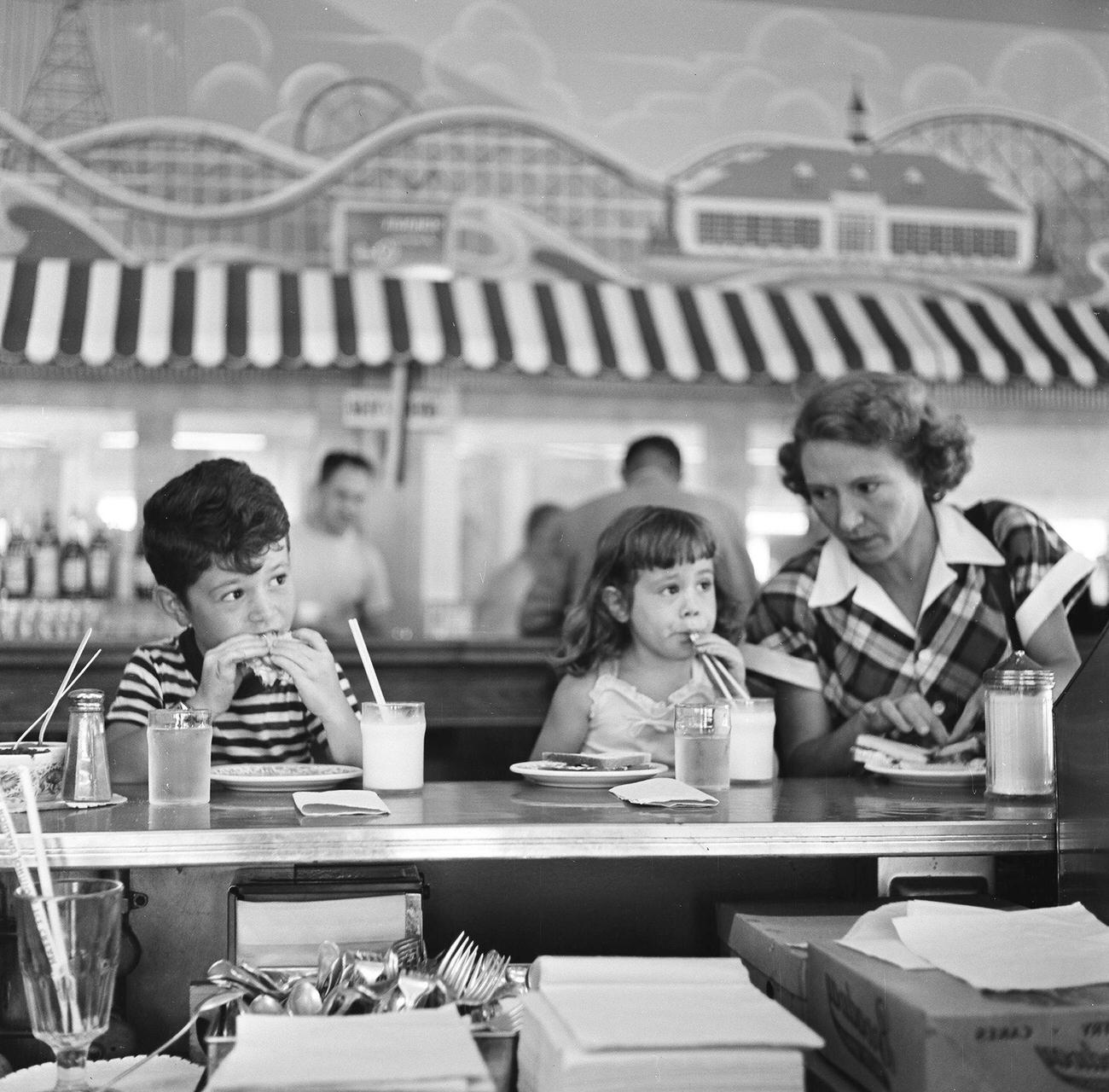 A Mother And Her Two Young Children Eat Lunch At A Counter, While Seated In An Eatery On Flatbush Avenue, 1948