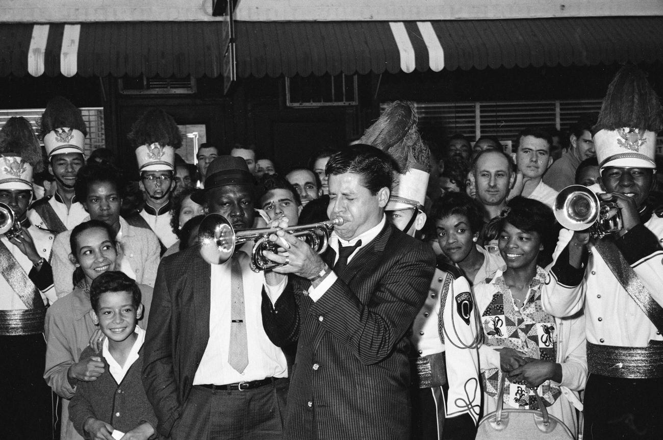 American Comedian And Actor Jerry Lewis Plays Trumpet Wth The St. Catherine Of Sienna Queensmen Band, In Front Of Alden Theater, Jamaica, 1961