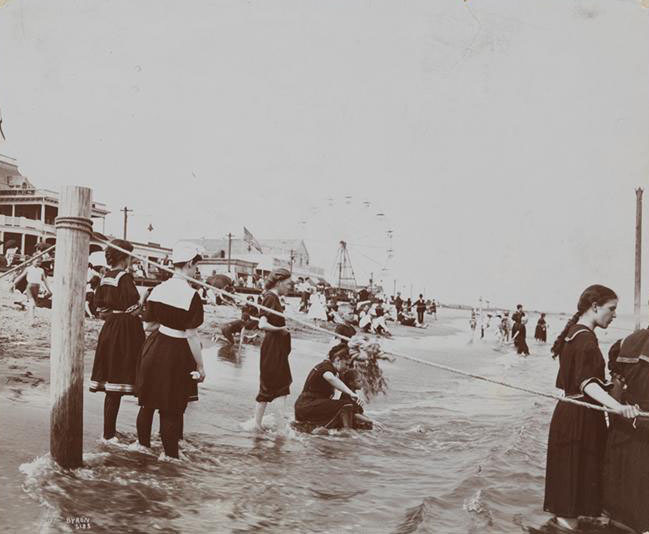 People Playing In The Water And Sitting On The Sand At Midland Beach, Viewed From The Water.