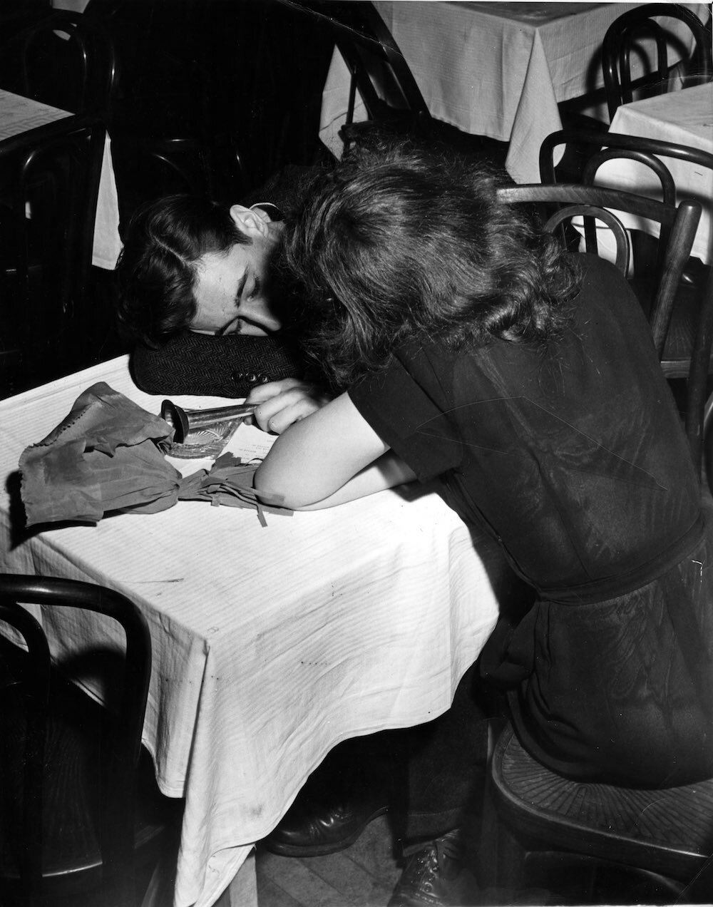 After New Year’s Eve festivities, a man sits with his head on a table, still holding onto a noise maker, next to a woman at the Stuyvesant Casino in New York.