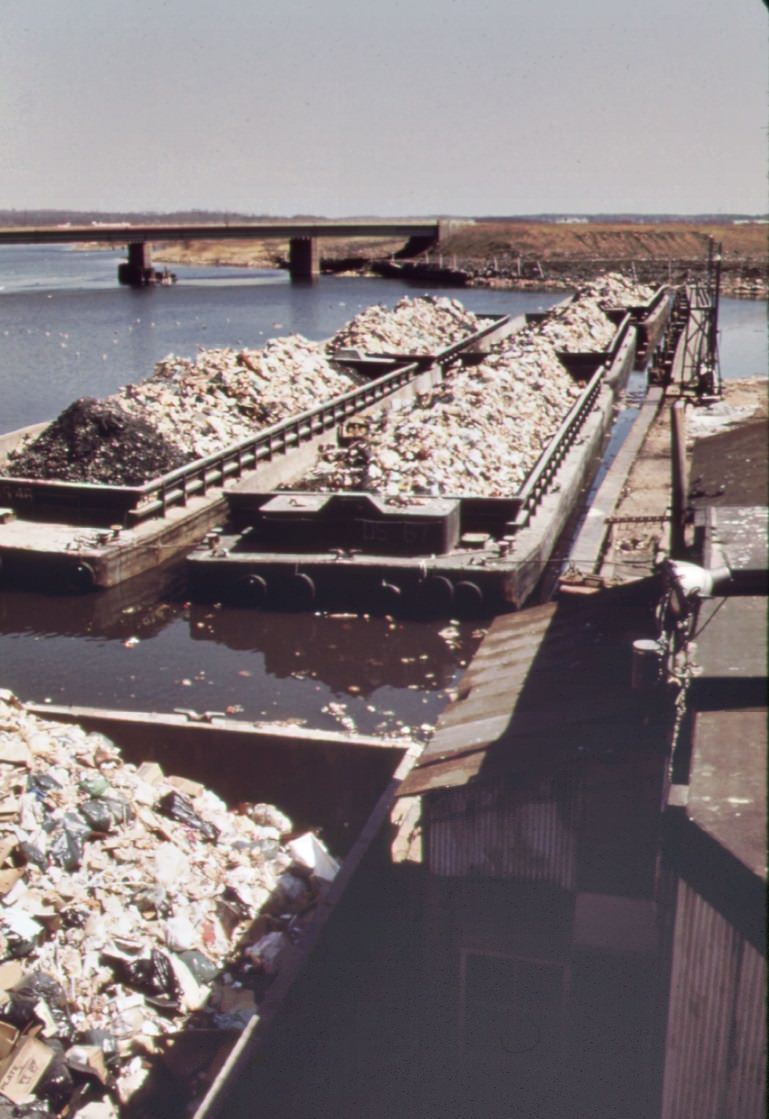 Solid Waste Is Towed Down The East River In Barges. At Staten Island, It Is Transferred To Carts, And Then Dumped At The Already Overflowing Landfill, 1970S