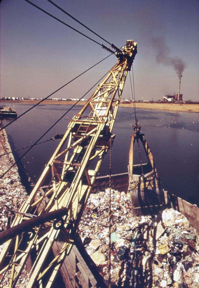 Unloading Garbage Scows At Staten Island. Carts Haul The Waste Material To The Edges Of The Vast Landfill Area. There The Refuse Is Dumped And Burned, 1970S