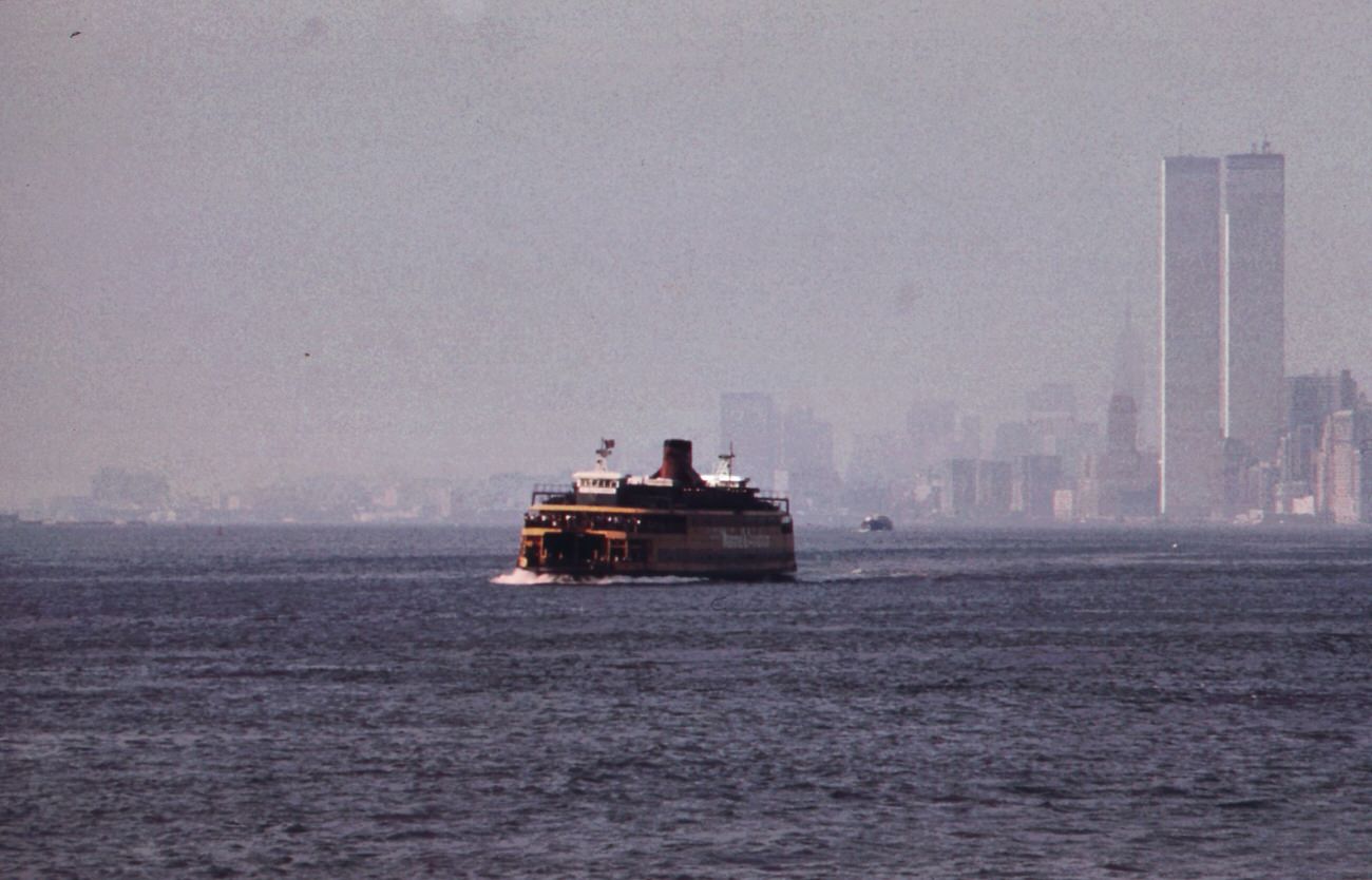 Staten Island Ferry With Smog-Obscured Skyline Of Lower Manhattan In Background. On The Right Are The Twin Towers Of The World Trade Center Overlooking The Hudson River, 1970S