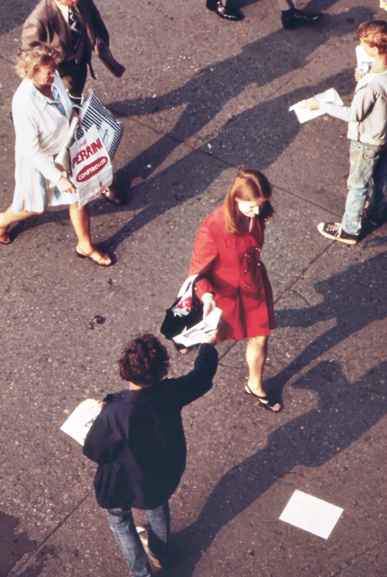 Without Breaking Stride, Homeward Bound Commuter At The Staten Island Ferry Terminal Reaches For Leaflet From Street Distributor, 1970S