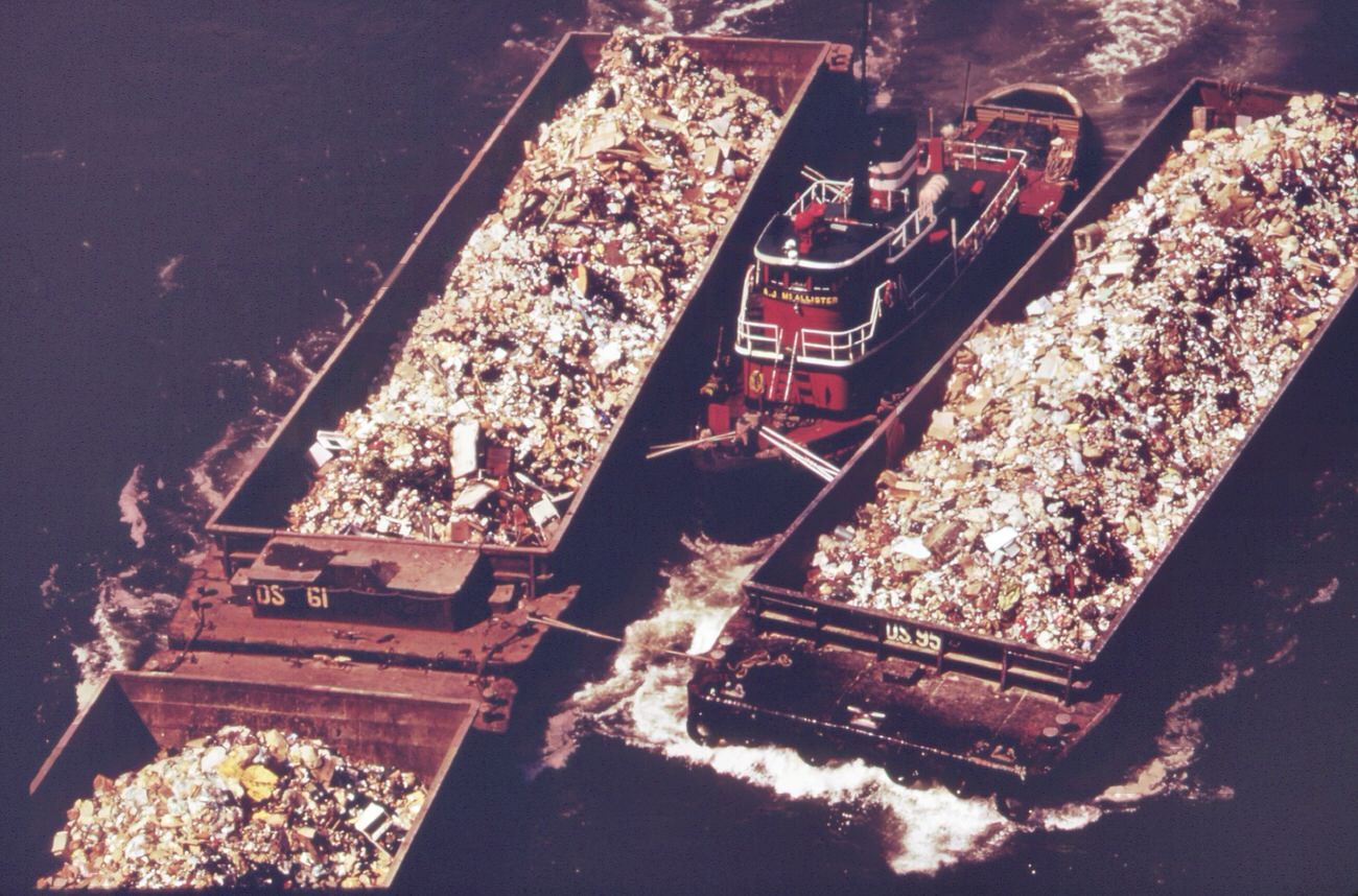 Part Of The 26,000 Tons Of Solid Waste That New York City Produces Each Day. Tugs Tow Heavily-Laden Barges Down The East River To The Overflowing Staten Island Landfill, 1970S