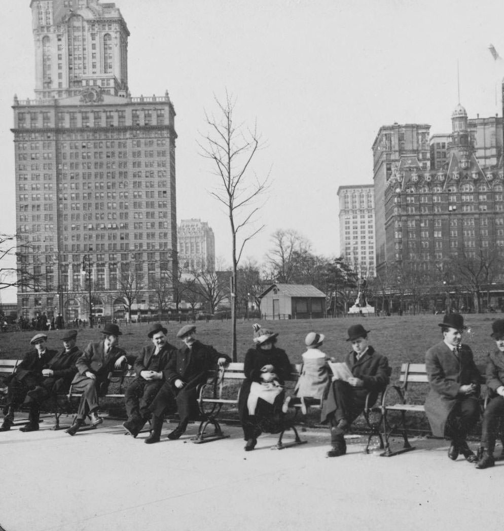 Battery Park: People Sitting On Park Benches, Buildings In The Background, New York City, 1895.