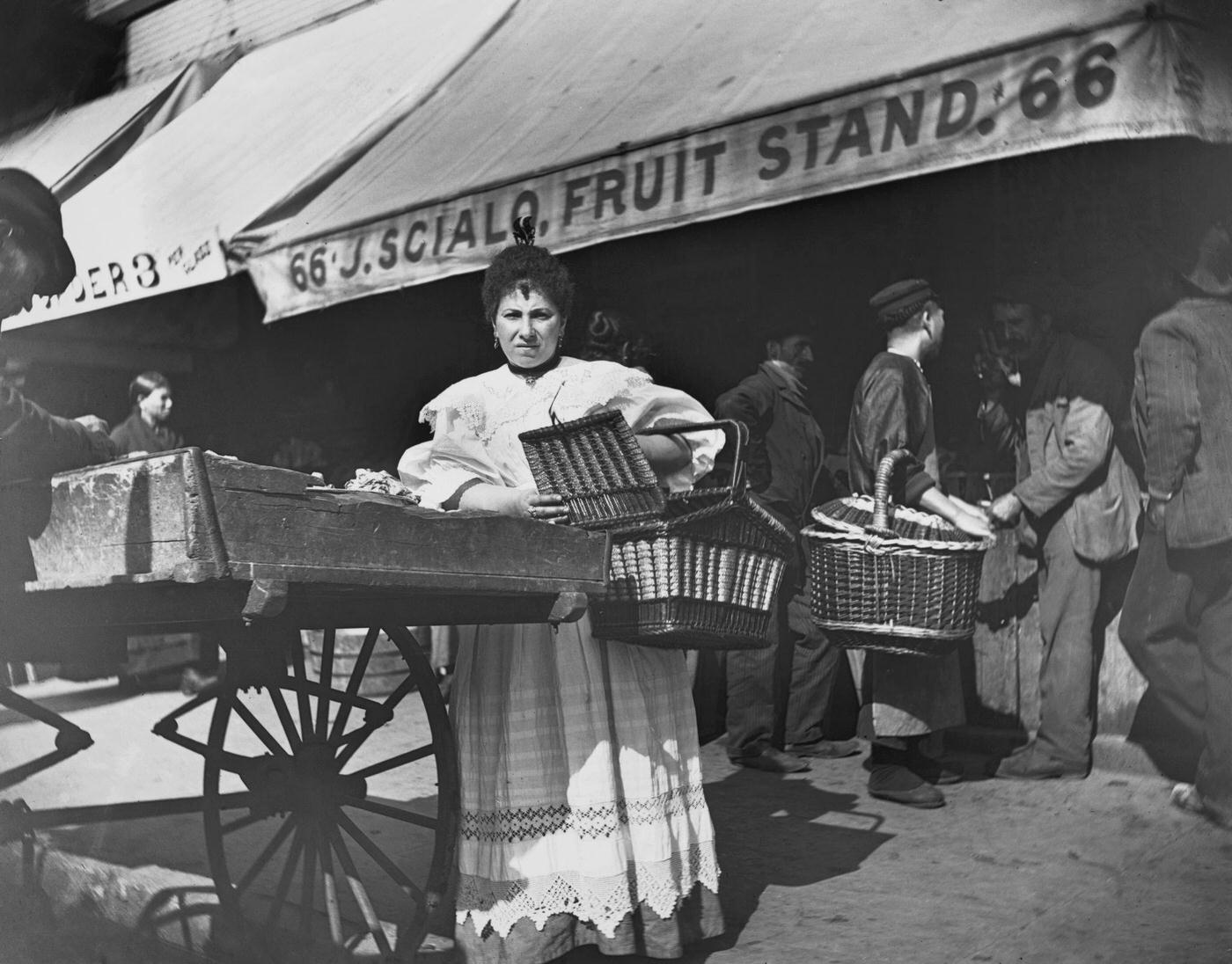 Woman Holding A Large Wicker Basket Buying From A Pushcart Vendor On Mulberry Street, New York City, 1897
