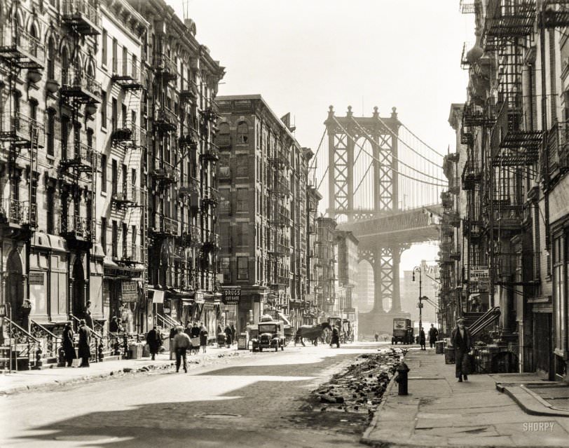 Looking Down Pike Street Toward The Manhattan Bridge, Street Half In Shadow, Rubble In Gutters, New York City, 1936