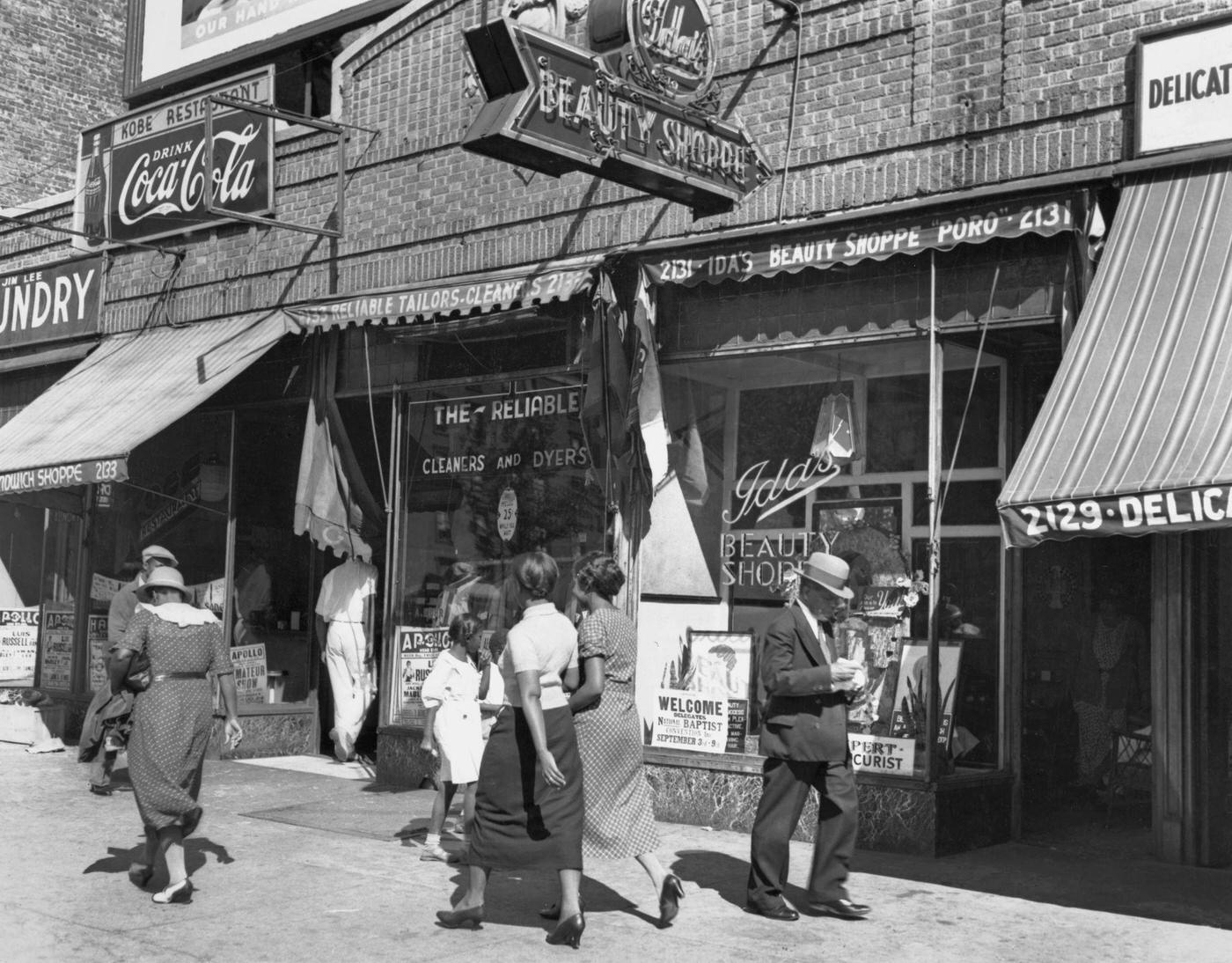 Pedestrians On The Sidewalk In Front Of Reliable Cleaners And Dyers On Lenox Avenue, Harlem, Manhattan, 1935.