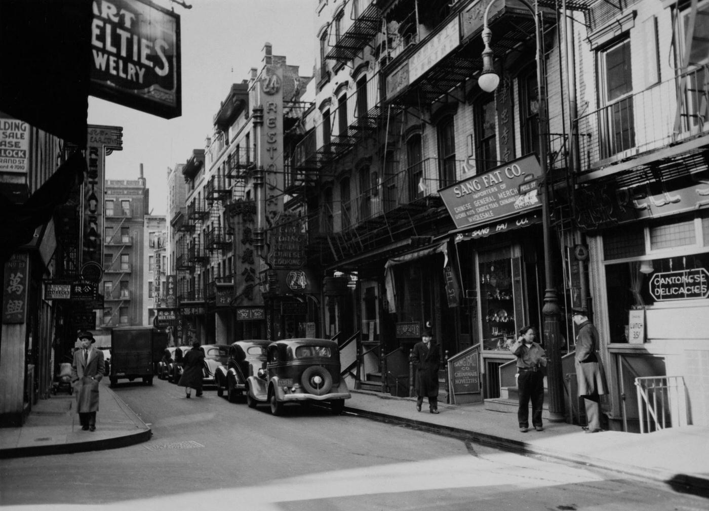 Cars Parked Along The Sidewalk With Pedestrians Outside Stores On Mott Street In Chinatown, Manhattan, 1945.