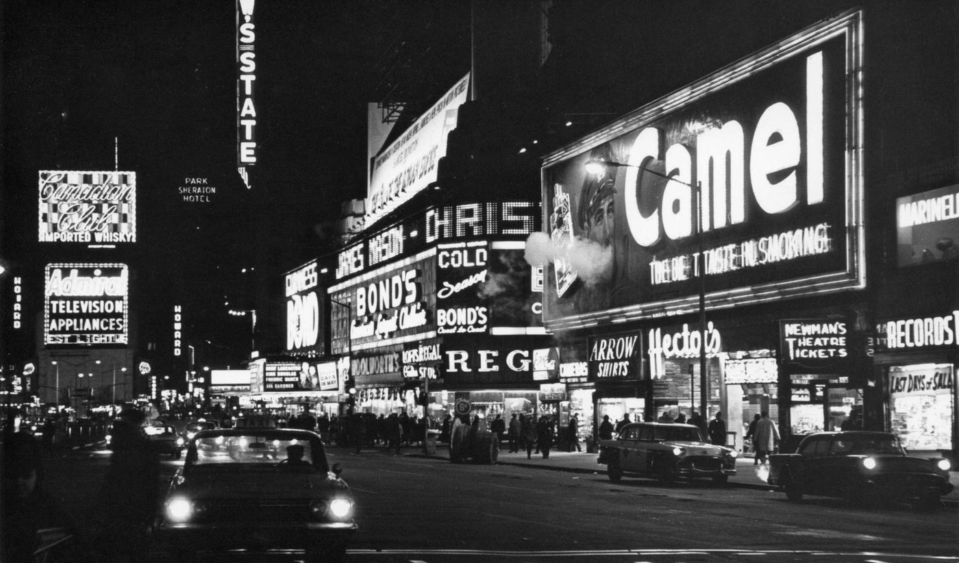 Nighttime View North Along Broadway Of Times Square With Neon Illuminated Billboard For Camel Cigarettes, Manhattan, 1964