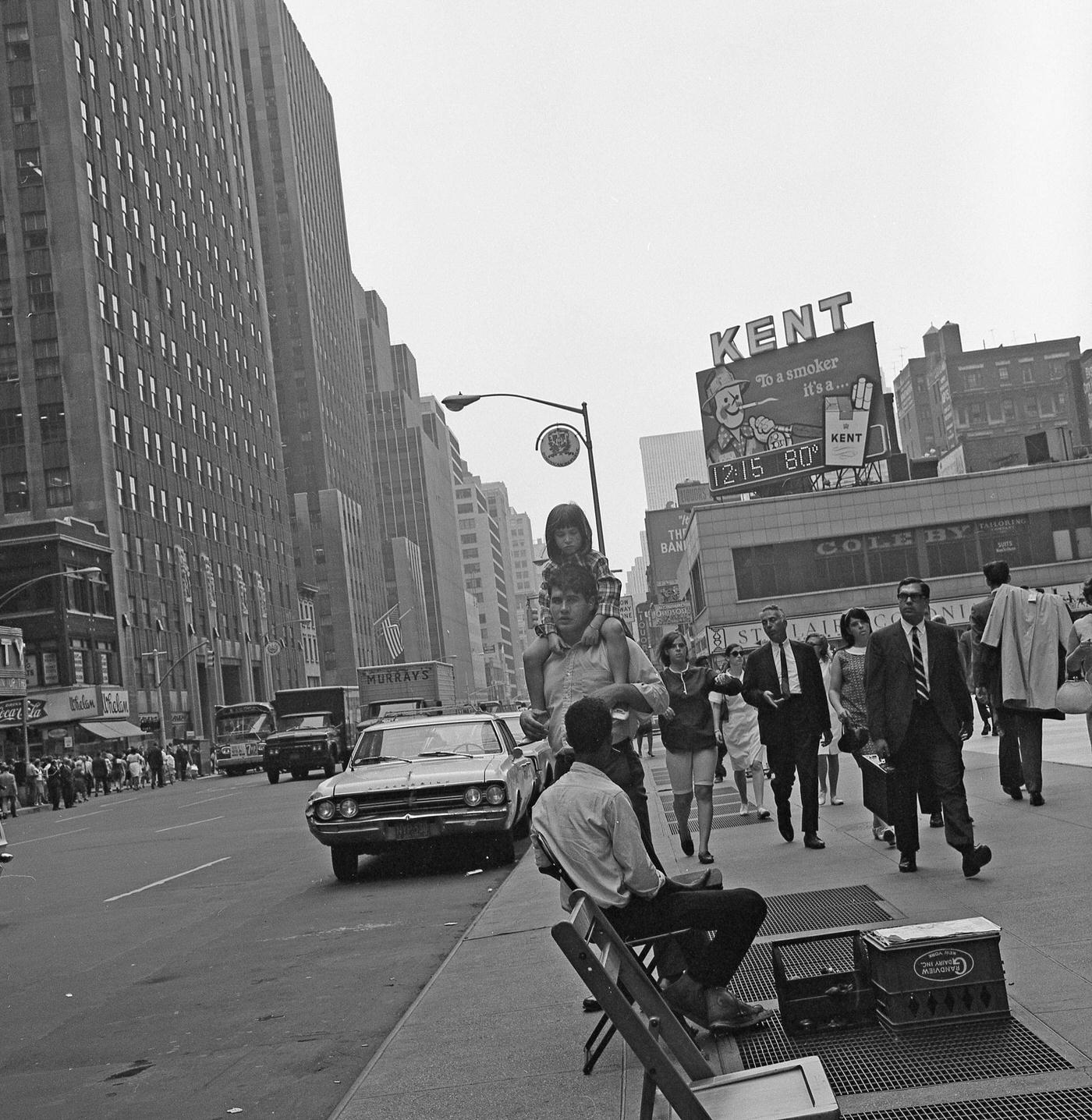 View Of Pedestrians, Including A Man Carrying A Child, On 6Th Avenue In Midtown, Manhattan, 1968