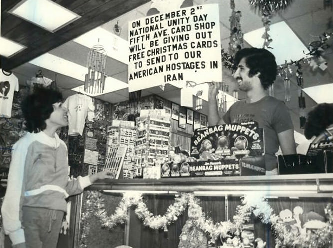 Steve Pedersen Shows Mary-Jo Roberts The Sign At The Fifth Avenue Card Shop In Staten Island Mall Offering Free Christmas Cards For Hostages, 1980.