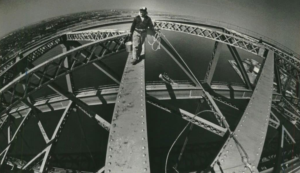 Fisheye Lens View Of Tommy Enright Walking Across Upper Girder Of Bayonne Bridge, Staten Island To The Left, 1969.