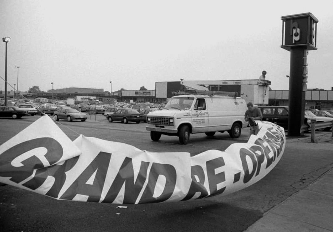 A Worker Installs A Grand Re-Opening Sign For The Weekend Celebration At Hylan Plaza, 1995.