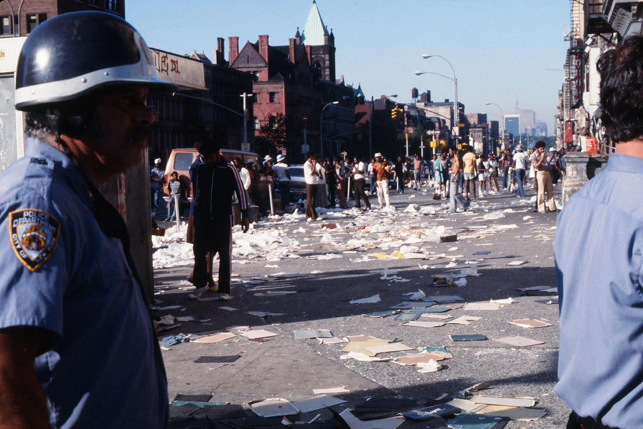 Police Officers And Passersby Stand In Front Of A Damaged Storefront Looting In The Wake Of The Blackout, Brooklyn, 1977