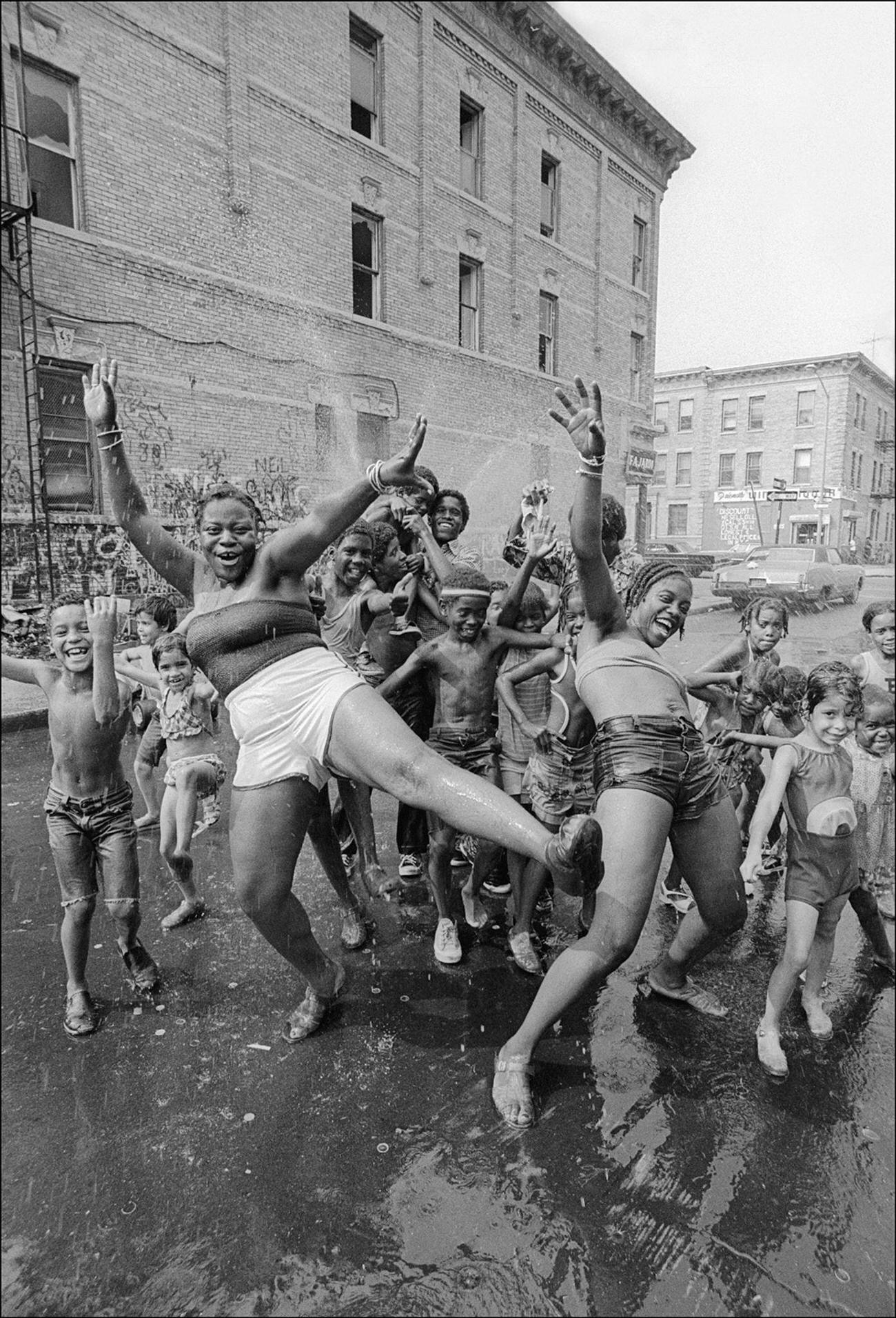 Children Dance Under The Spray From A Fire Hydrant Sprinkler In Brooklyn'S Bushwick Neighborhood, Brooklyn, 1977