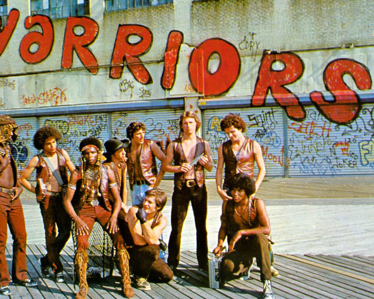 Cast Of 'The Warriors' Pose In Front Of Graffiti-Covered Store Fronts At Coney Island, Brooklyn, 1979