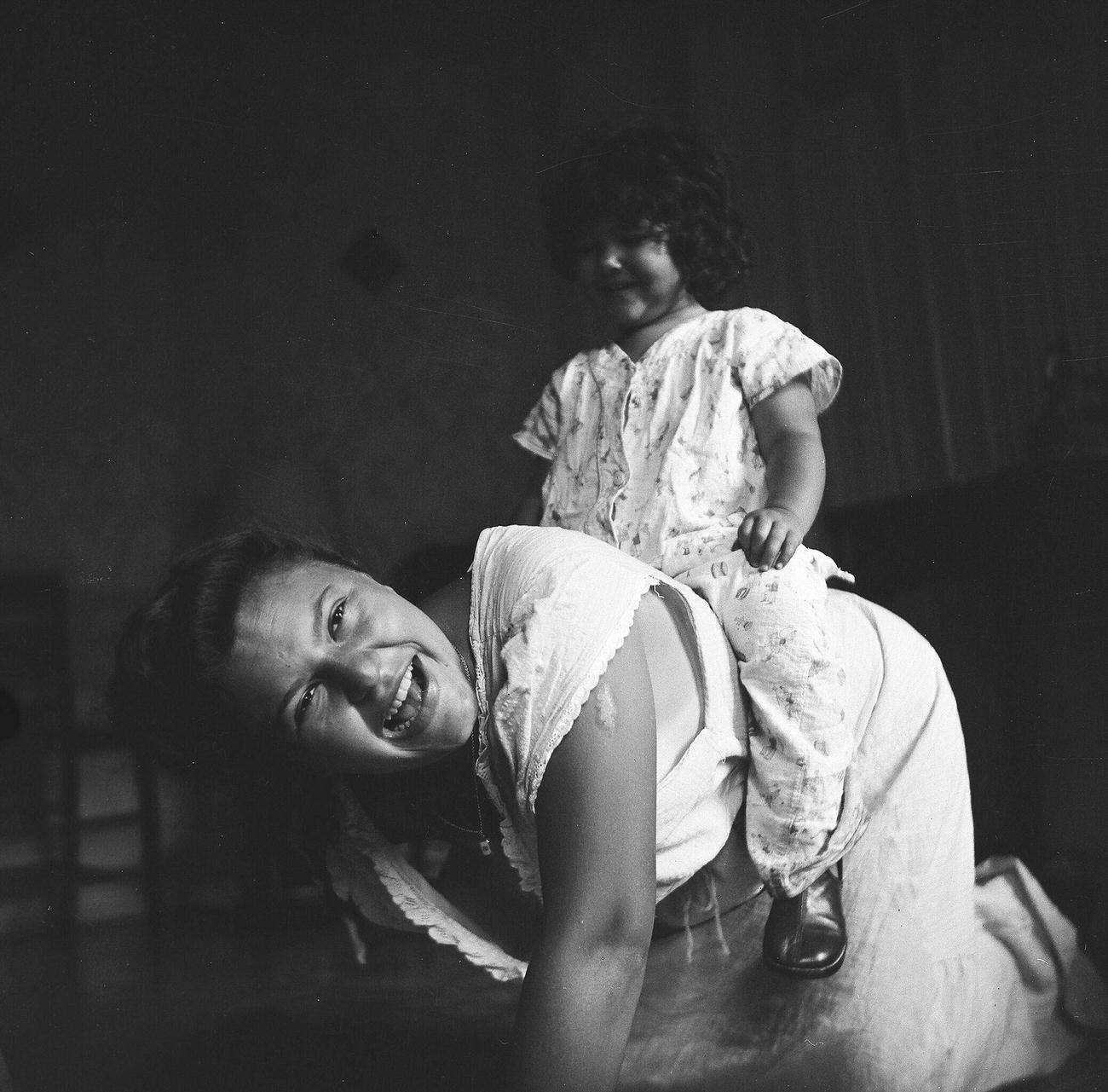 Woman Giving A Young Girl A Piggy Back Ride, 1944