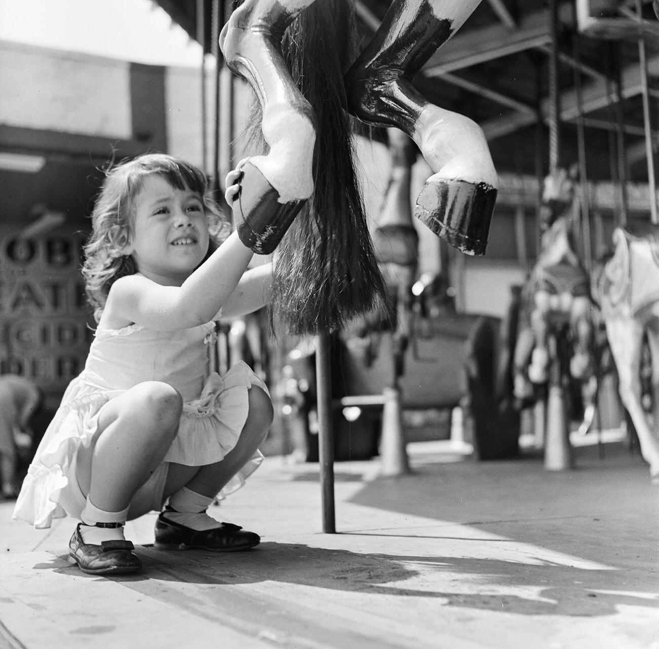 Girl Holding Carousel Horse Hoofs, 1948