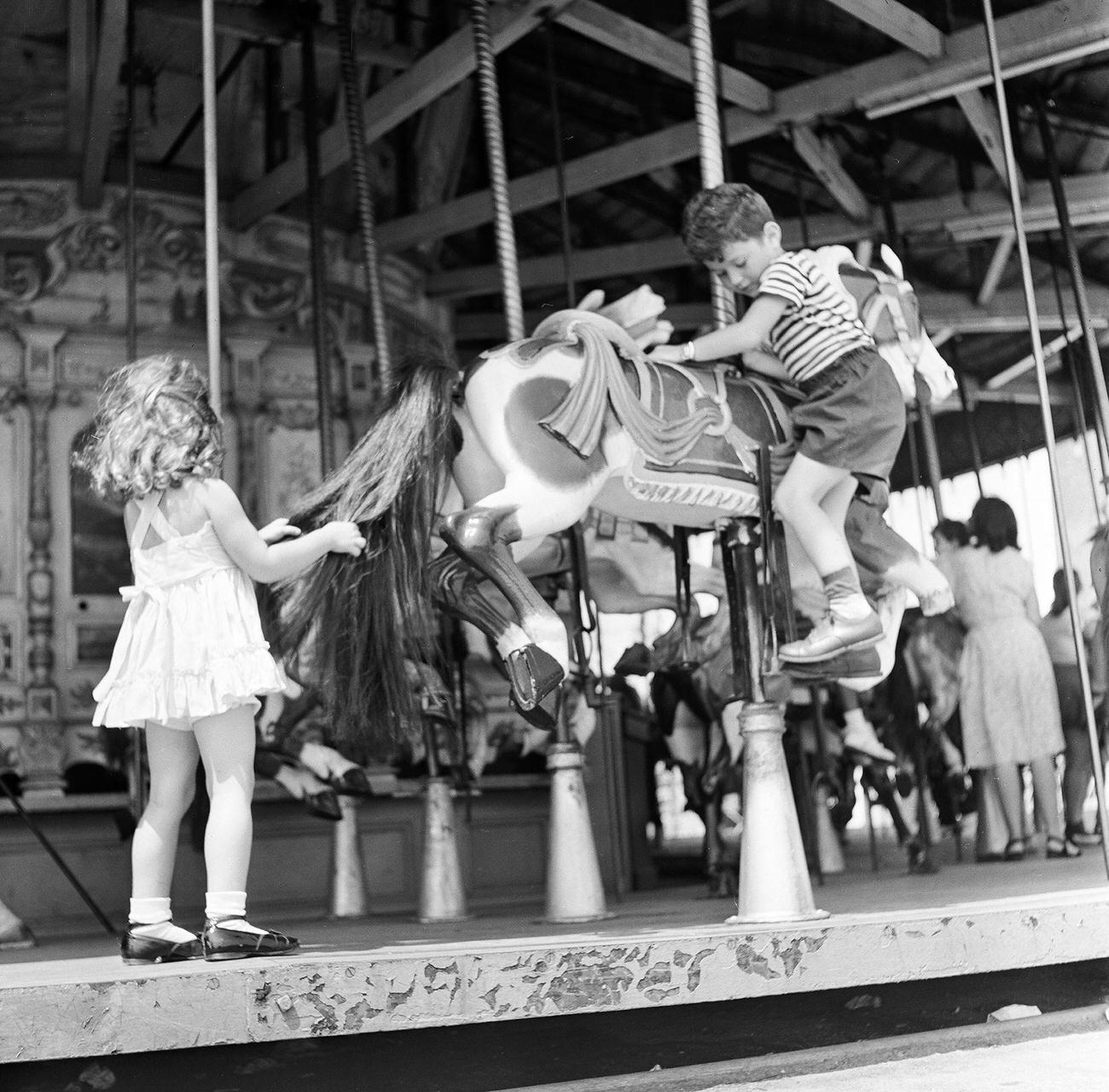 Siblings At Carousel, Boy Climbing On Horse, 1948