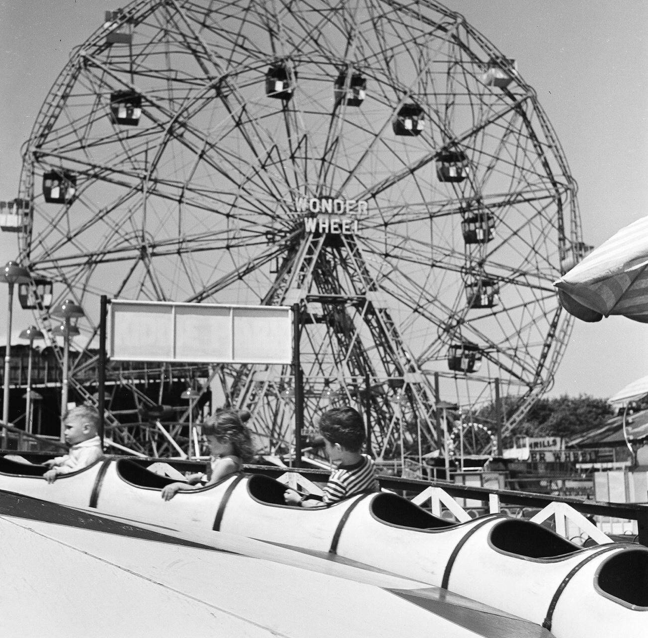 Three Children Enjoy A Ride With The 'Wonder Wheel' Ferris Wheel In The Background At Coney Island, 1948