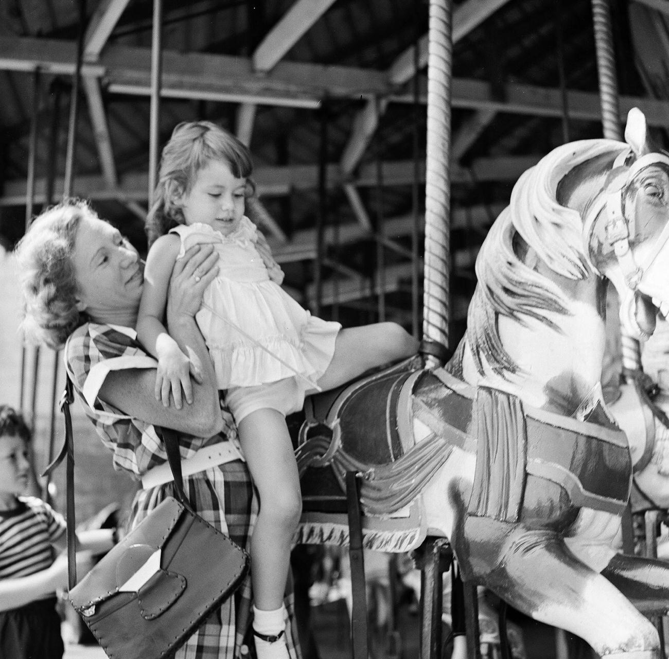 Mother Lifts Daughter Onto A Carousel Horse At Coney Island, 1948