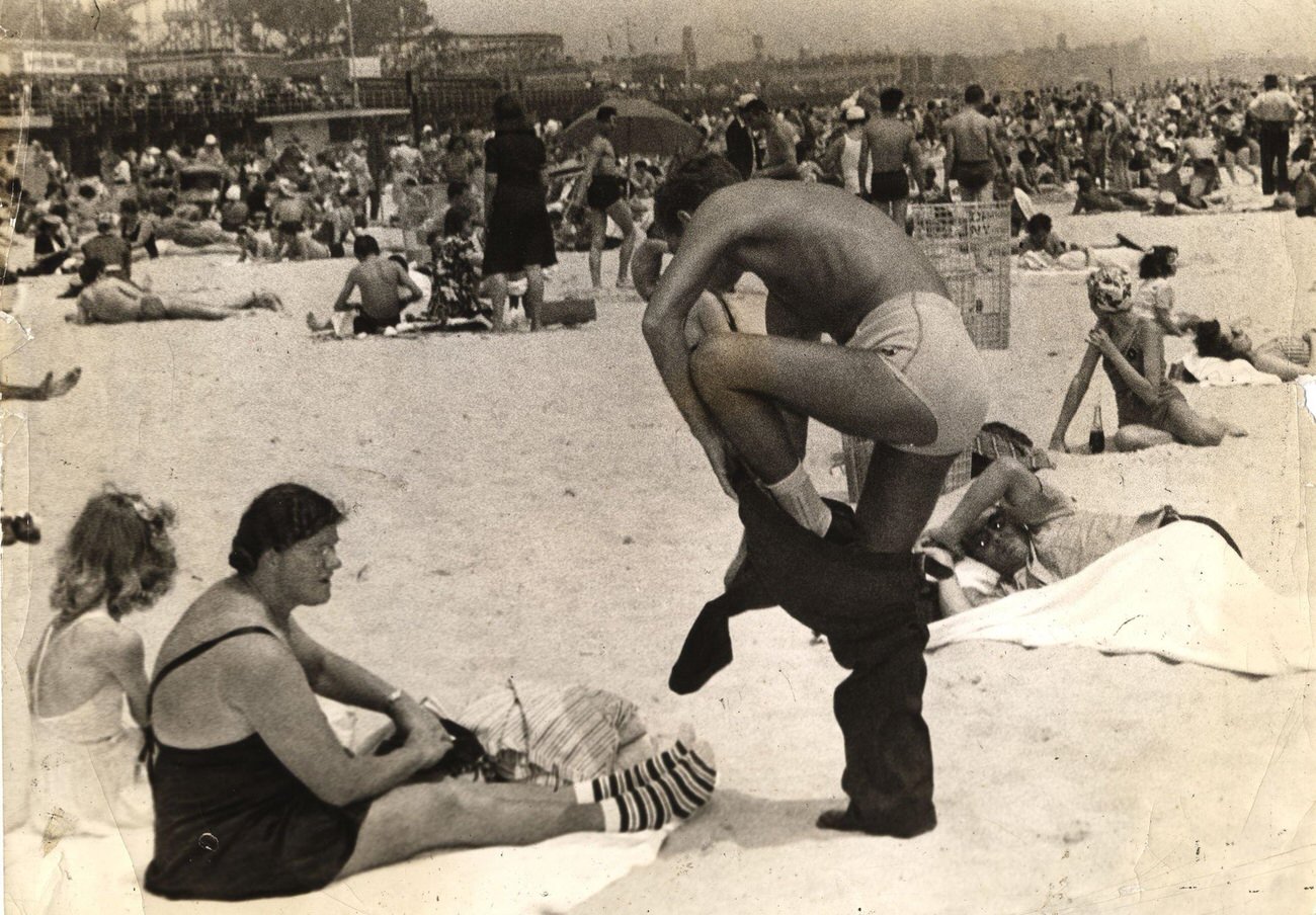 Man Struggles Out Of Trousers On Crowded Beach, Early 1940S