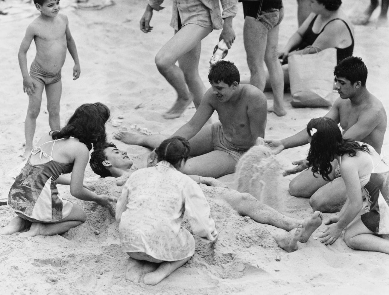 Teenagers Burying A Friend In Sand At Coney Island, August 13, 1944