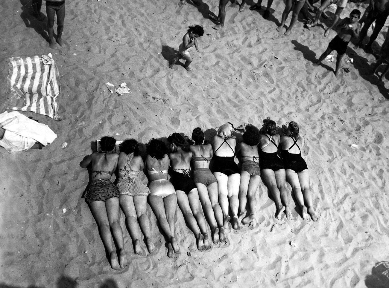 Nine Women Lying Face Down On Coney Island Beach, Aerial View