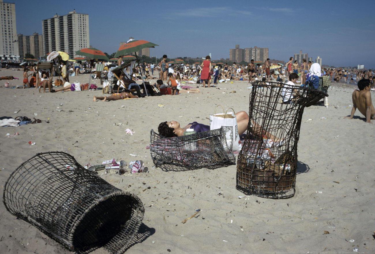 Woman Lying Behind Damaged Trash Cans On Coney Island Beach, 1971
