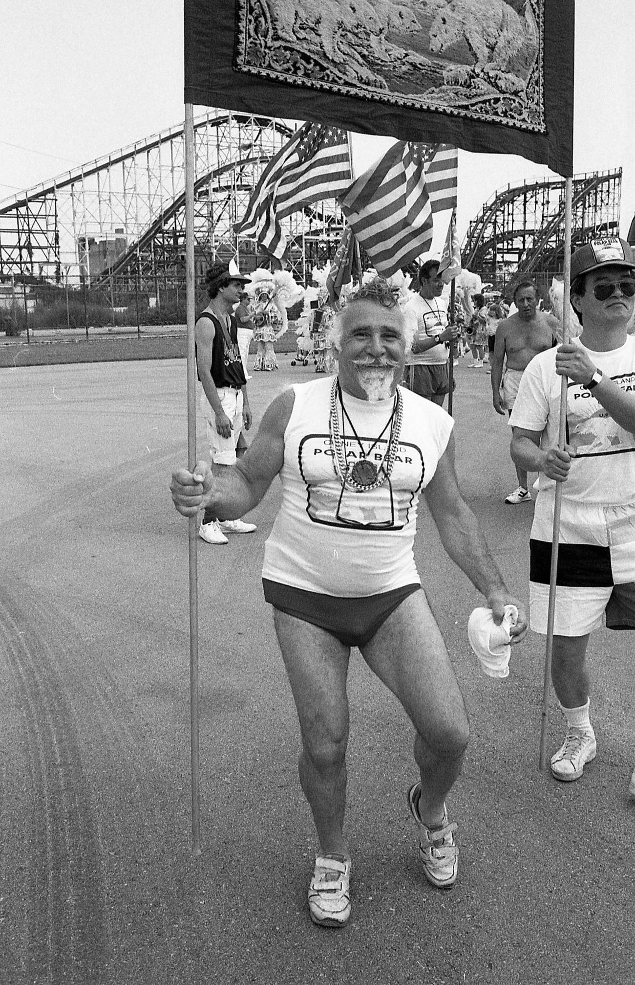 Man Represents Polar Bear Club With Group At Coney Island Mermaid Parade, Cyclone Visible, 1989