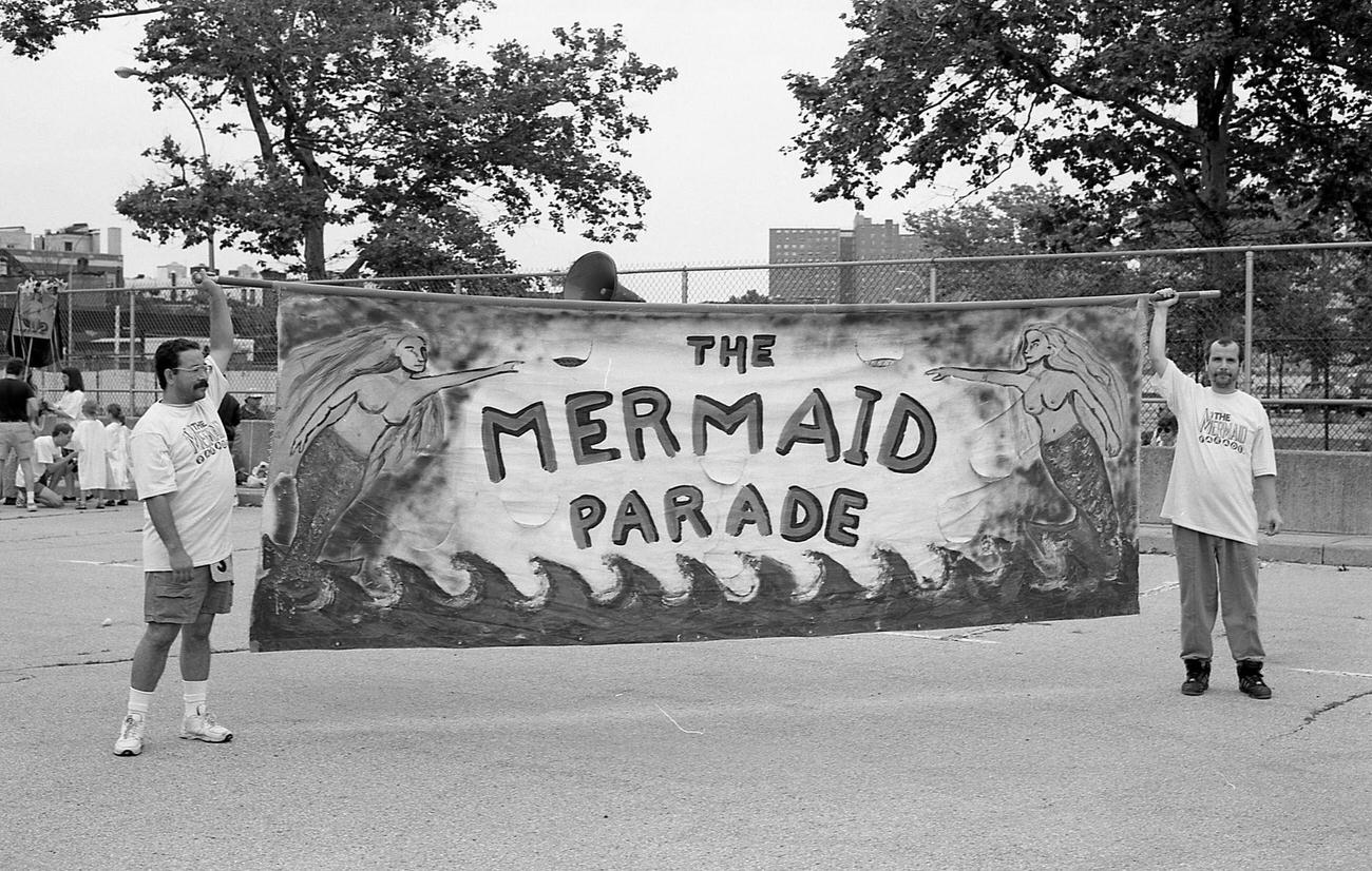 Men Holding Banner For Mermaid Parade In Astroland Parking Lot, 1995