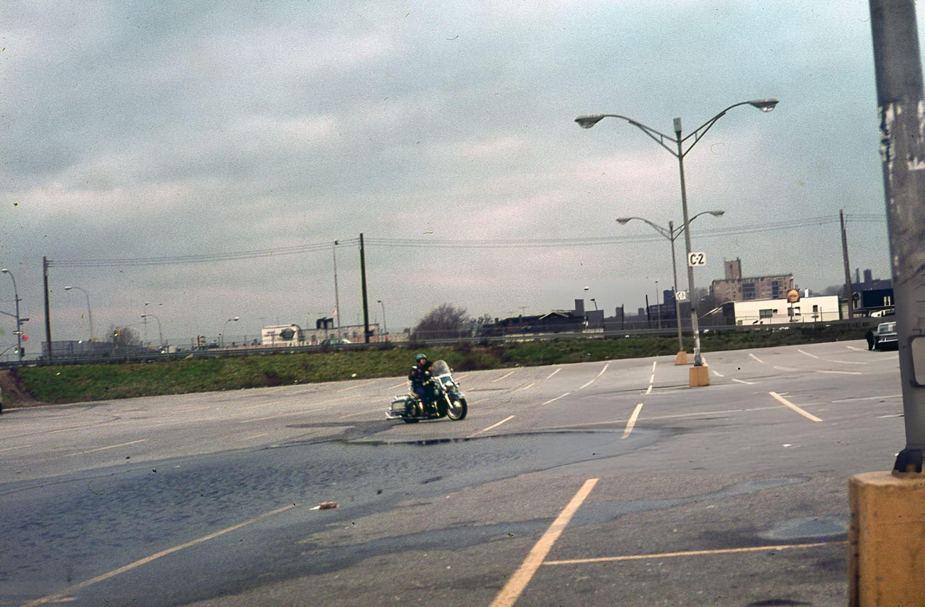 Two Individuals Ride Through An Empty Bronx Parking Lot On A Motorcycle, 1976.