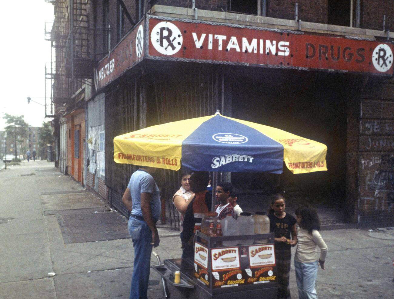 A Hot Dog Seller Operates In Front Of Burnt-Out Shops And A Tenement Block In The South Bronx, New York City.