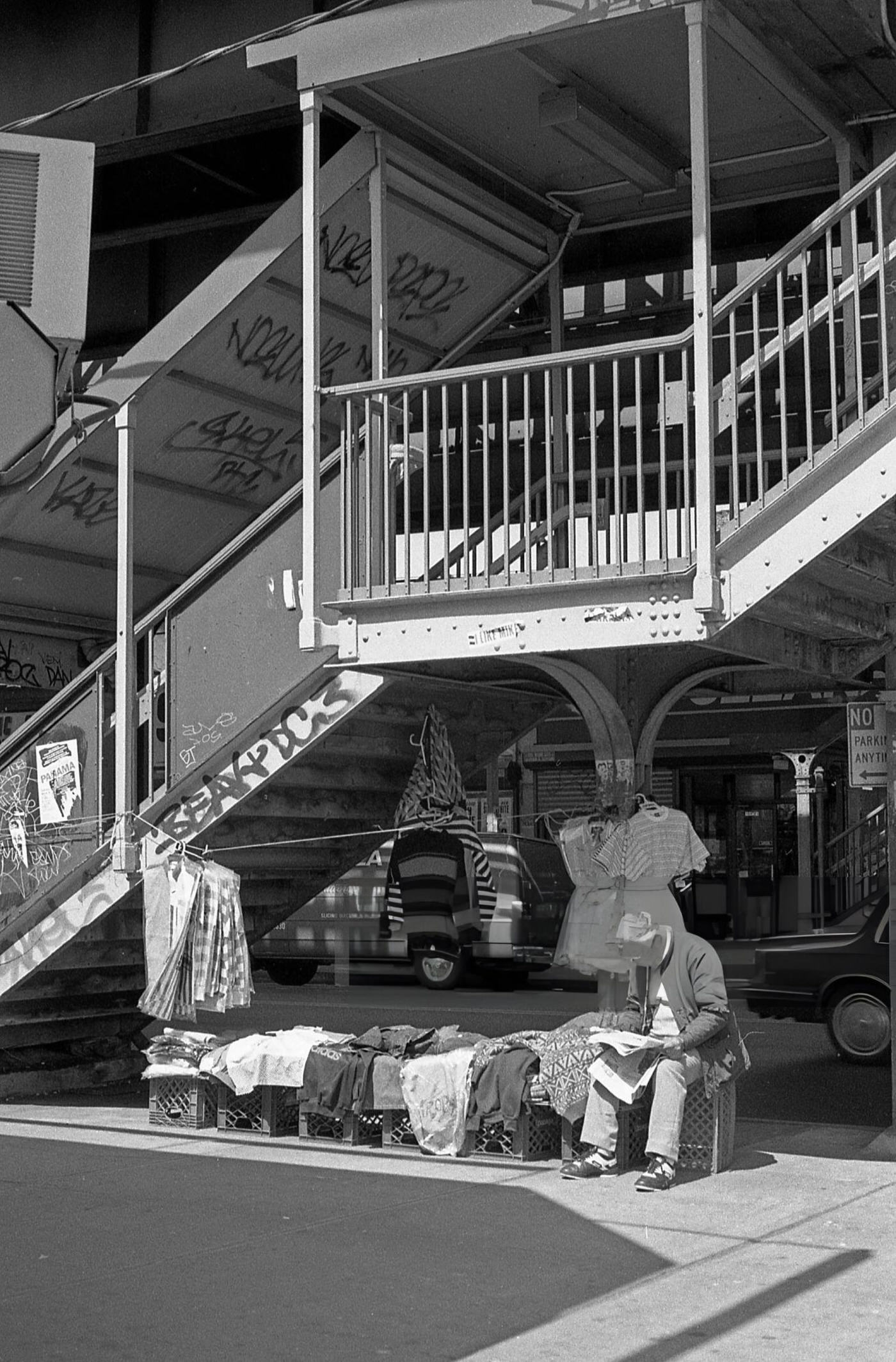 A Street Vendor Waits To Sell Clothing Next To The 103Rd Street Elevated Subway Station In Corona, Queens, 1990S.
