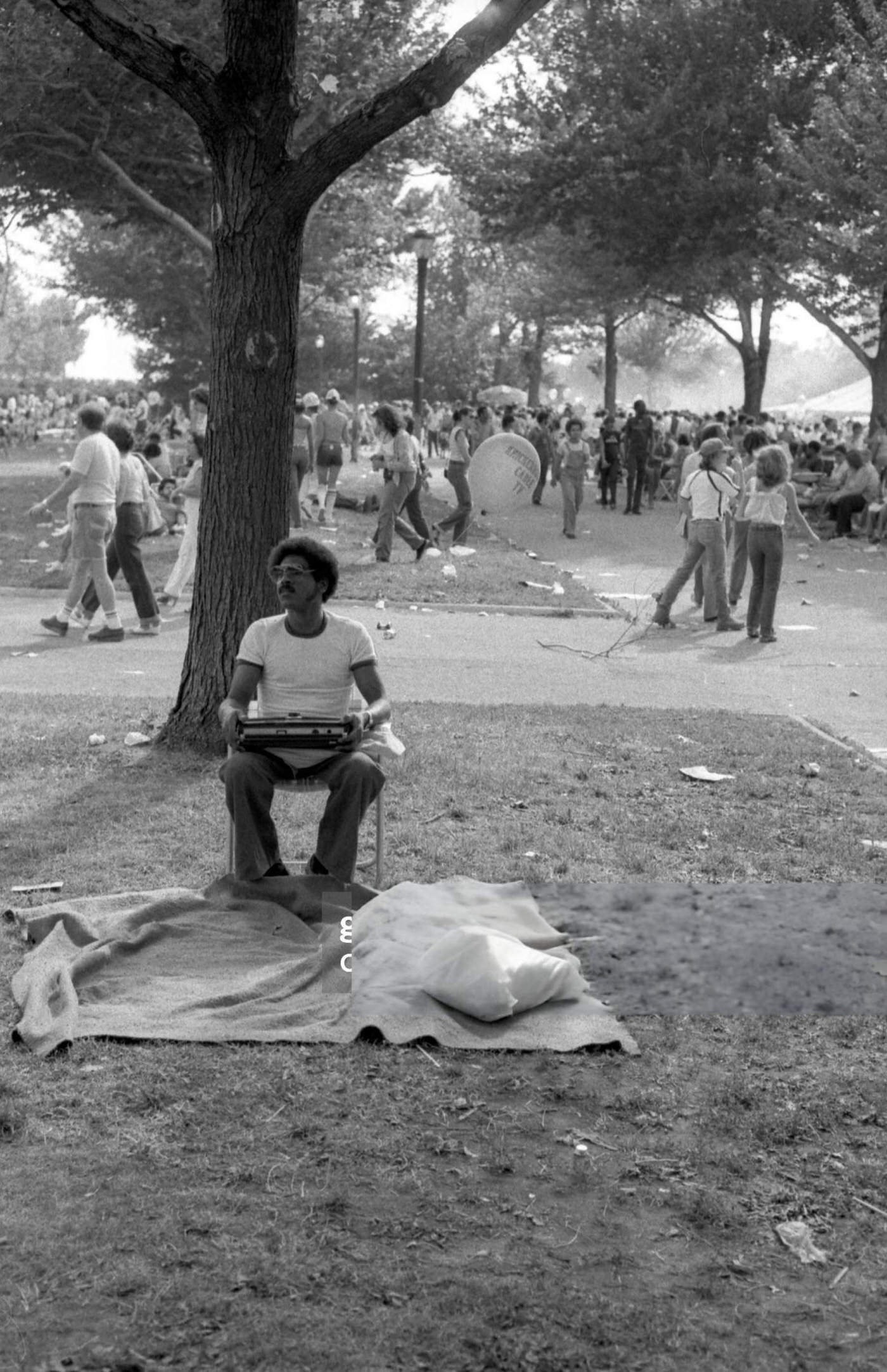 A man sits in a chair with a radio in his lap in Flushing Meadows Park, Corona, Queens, 1980.