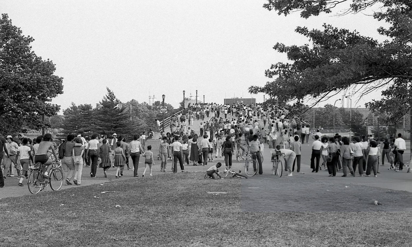 People walk over a pedestrian bridge in Flushing Meadows Park, Corona, Queens, 1980.