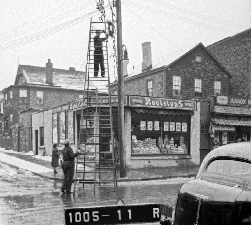 People Hanging Up Or Taking Down Christmas Decorations Outside 91 Richmond Ave With Roulston'S Grocery Store In The Background, Staten Island, Circa 1940.
