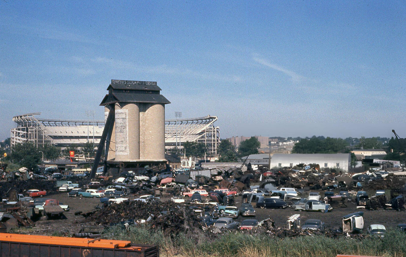 Junkyard On Willets Point Boulevard In Queens' Corona Neighborhood With The Municipal Stadium Under Construction In The Background, 1963.