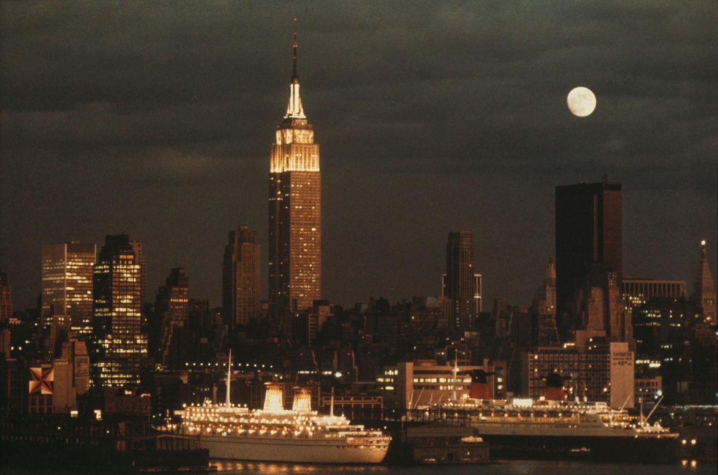 Night View Of The Empire State Building, Ships In New York Harbor, And Skyline In Manhattan, 1974.