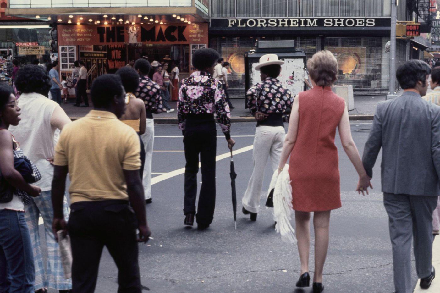 Pedestrians Crossing A Road Lined With Shops In Upper Manhattan, 1975.