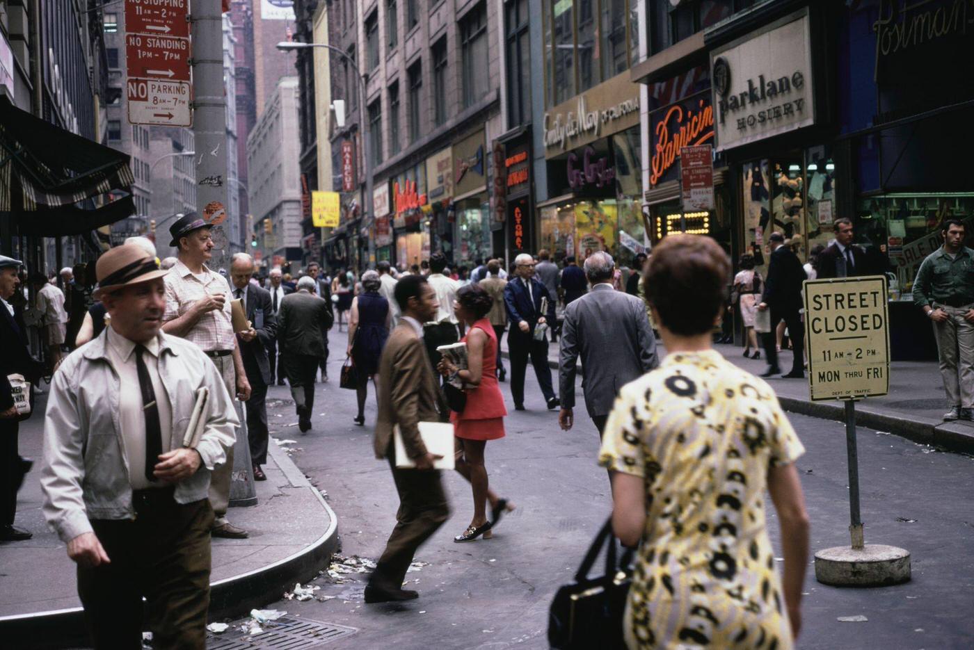 Pedestrians Crossing A Road Lined With Shops In Downtown Manhattan, 1975.