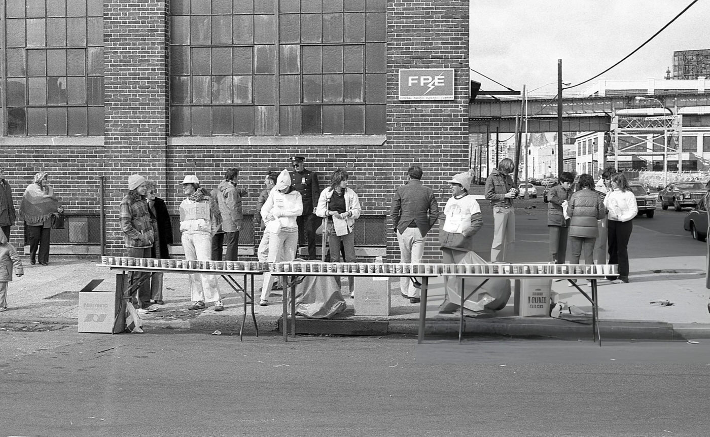 Spectators Lining Up On The Sidewalk Behind Curbside Water Stations On Crescent Street During The New York City Marathon, Queens, 1980.