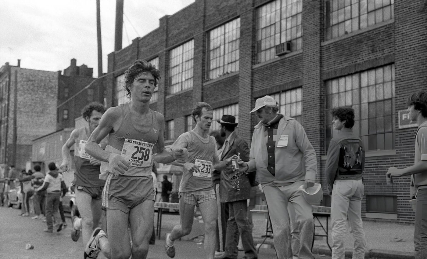 Three Runners As They Pass The 14-Mile Marker On Crescent Street During The New York City Marathon, Queens, 1980.