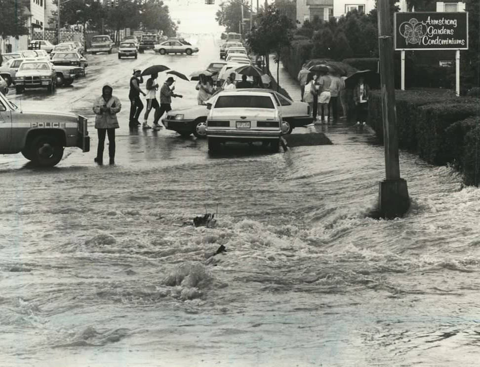 A River Flows On Armstrong Avenue In Great Kills As Police Direct Pedestrians From The Flooded Street, 1989.
