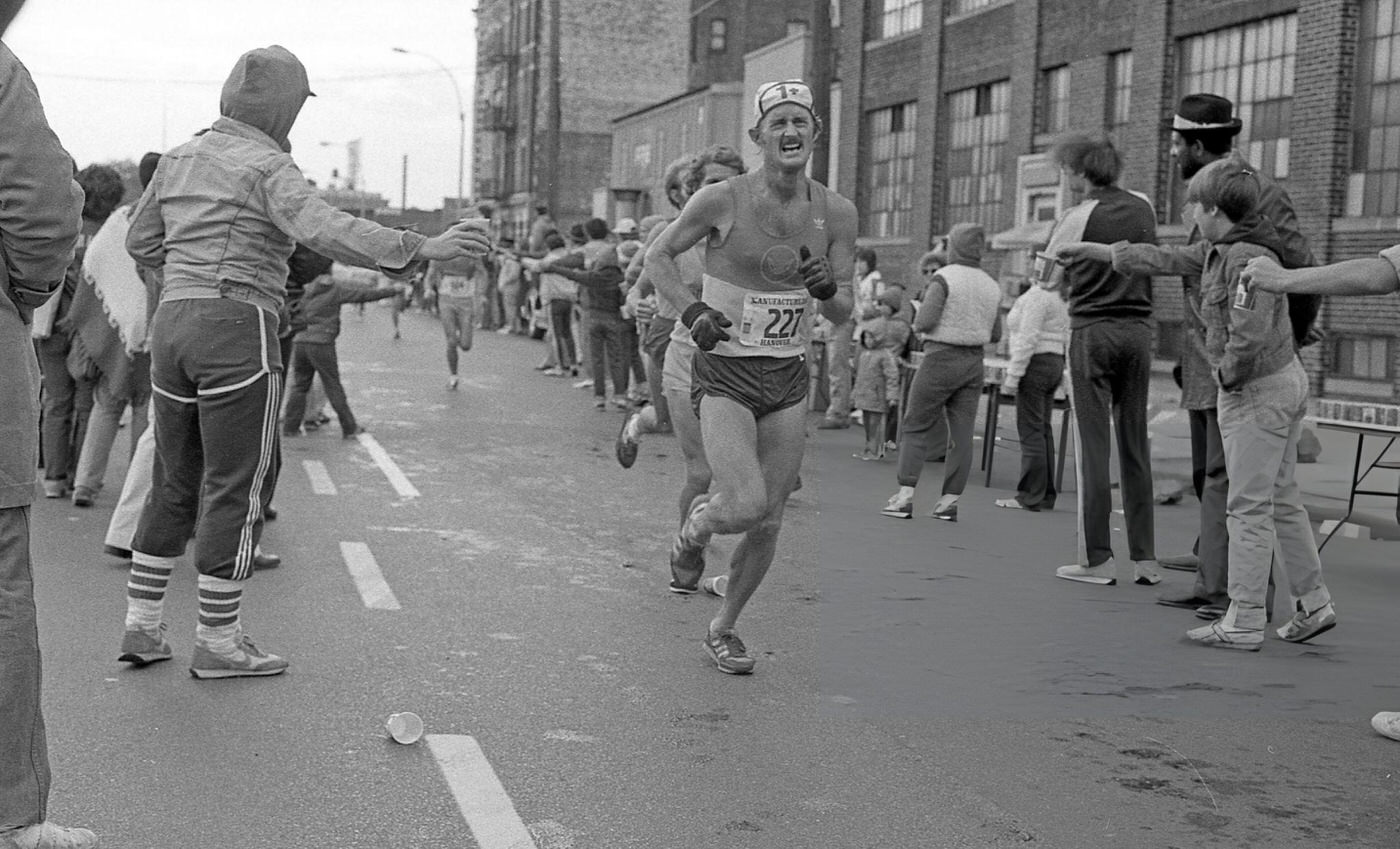 Runners Pass The 14-Mile Marker On Crescent Street During The New York City Marathon, Queens, 1980.