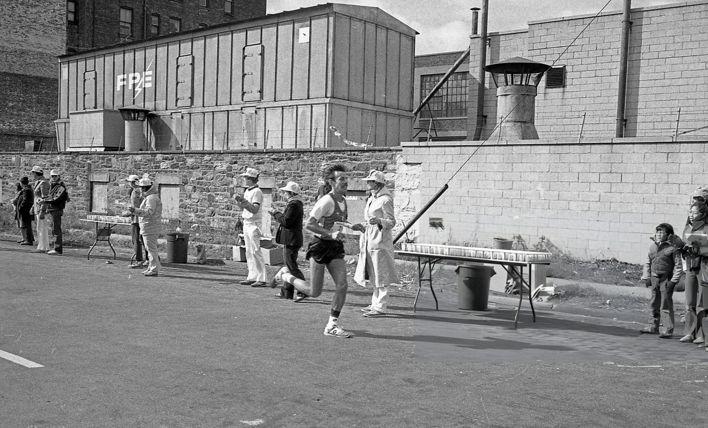 A Runner Passes The 14-Mile Marker On Crescent Street During The New York City Marathon, Queens, 1980.