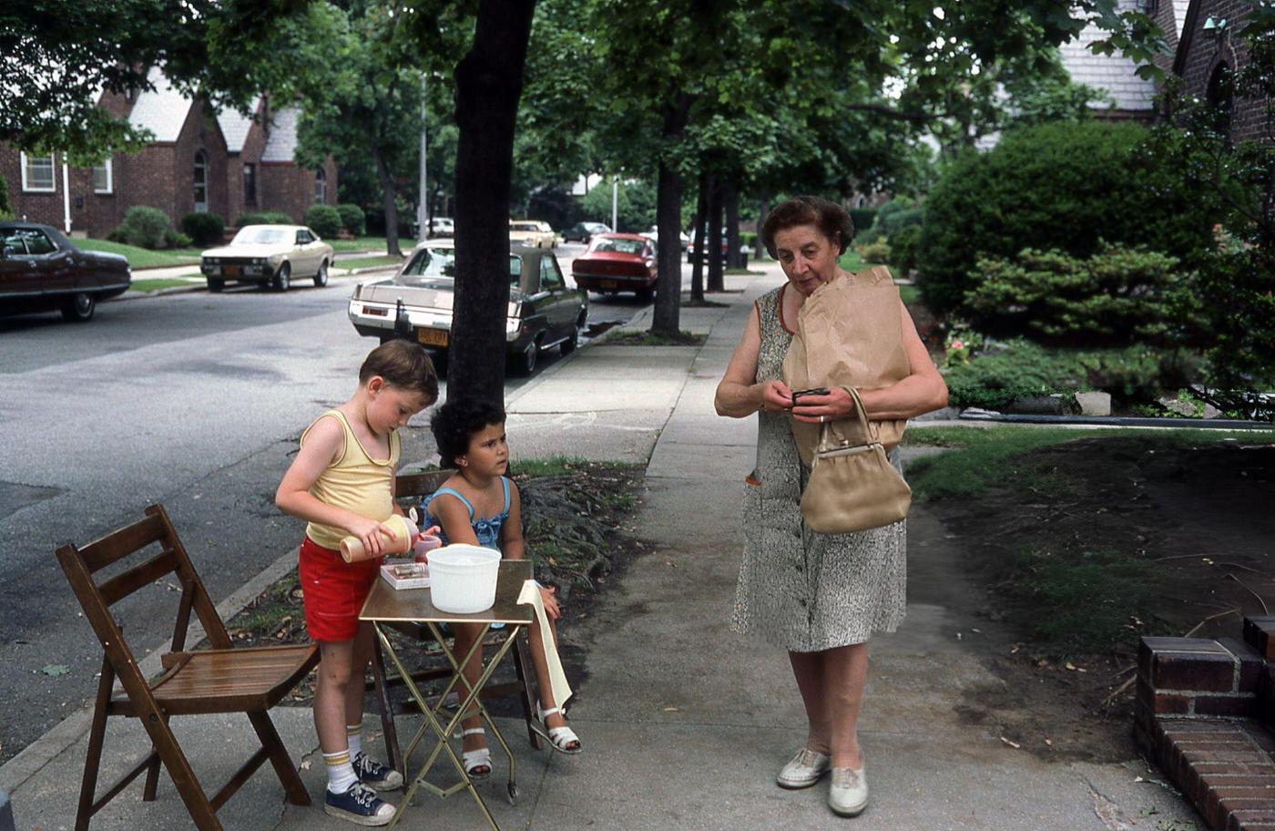 Two Children At A Lemonade Stand Pouring A Drink For A Passerby On Fitchett Street In Rego Park, Queens, 1970S.