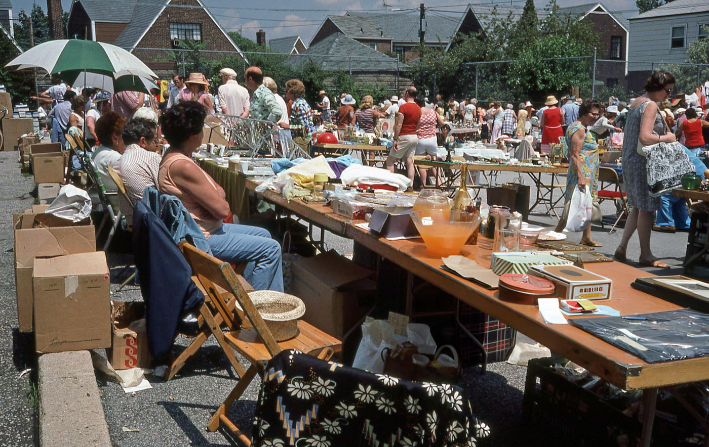 Vendors Sitting At Their Tables At An Outdoor Flea Market On Woodhaven Boulevard In Rego Park, Queens, 1970S.